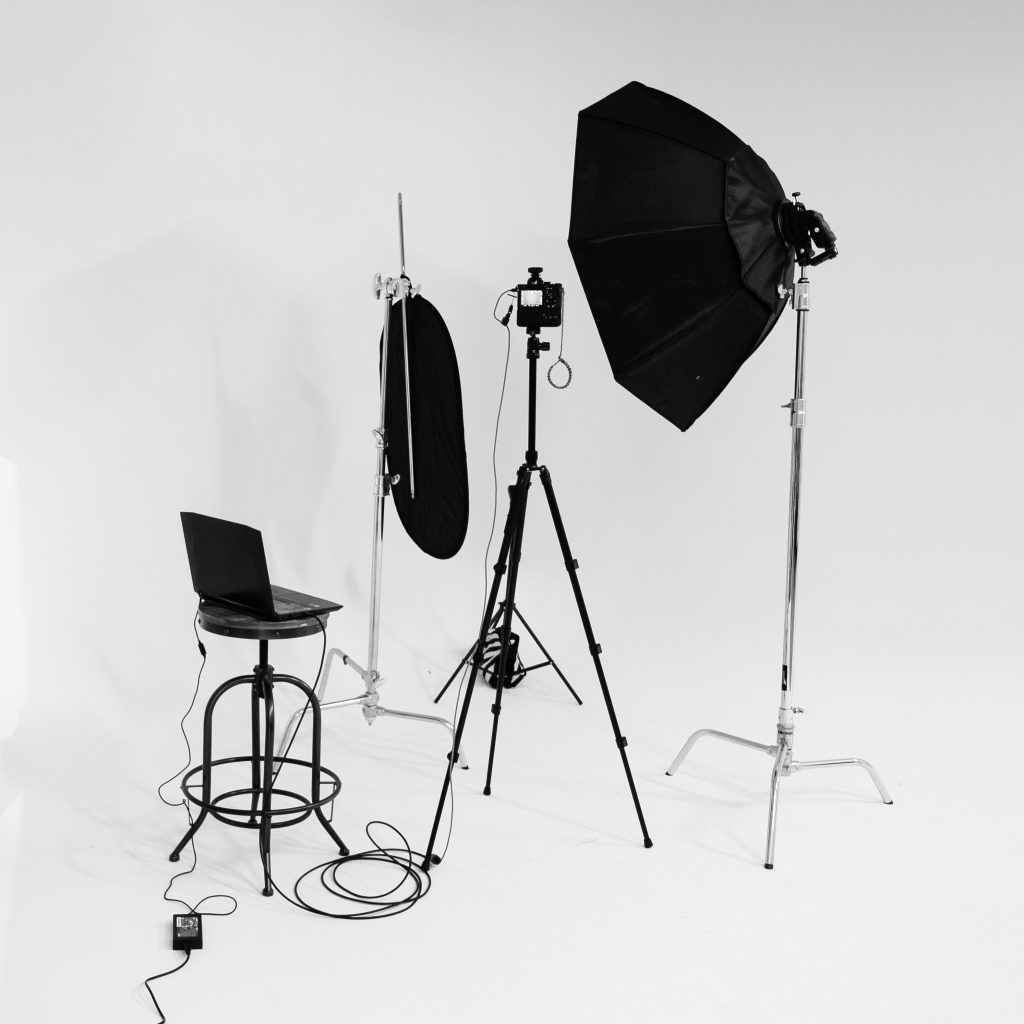 Camera, laptop and lighting equipment on a white backdrop